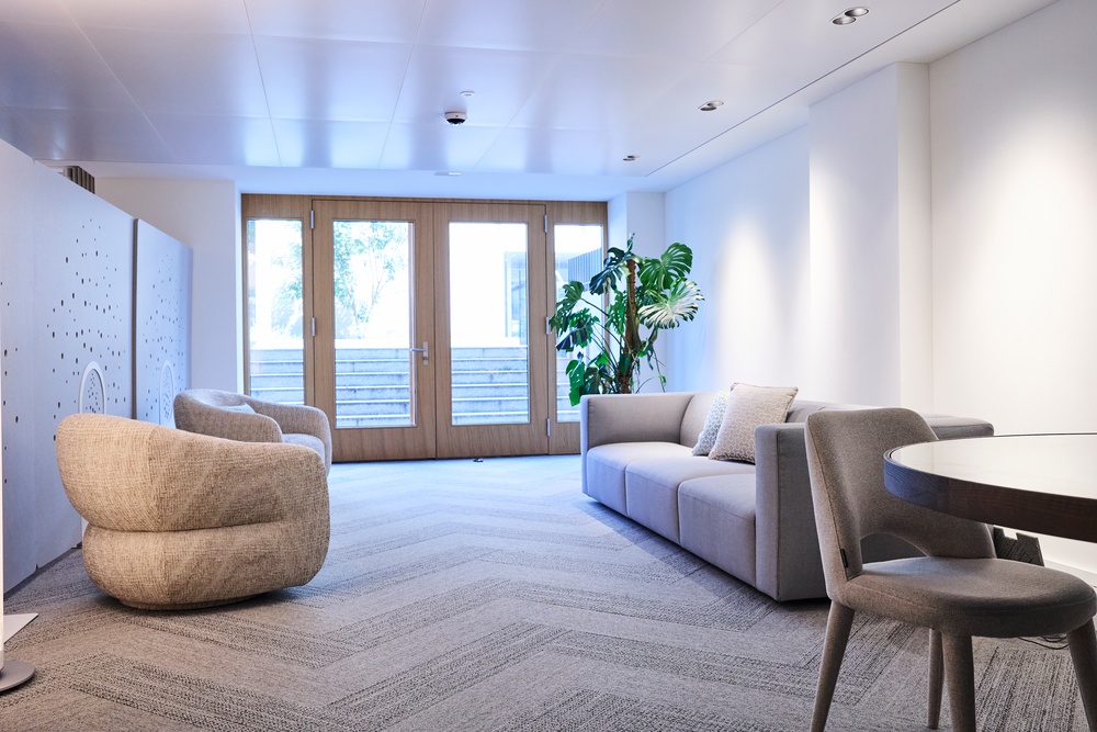 Lounge mit Sofa, Sesseln und Fenstertür im Elysium Institut
